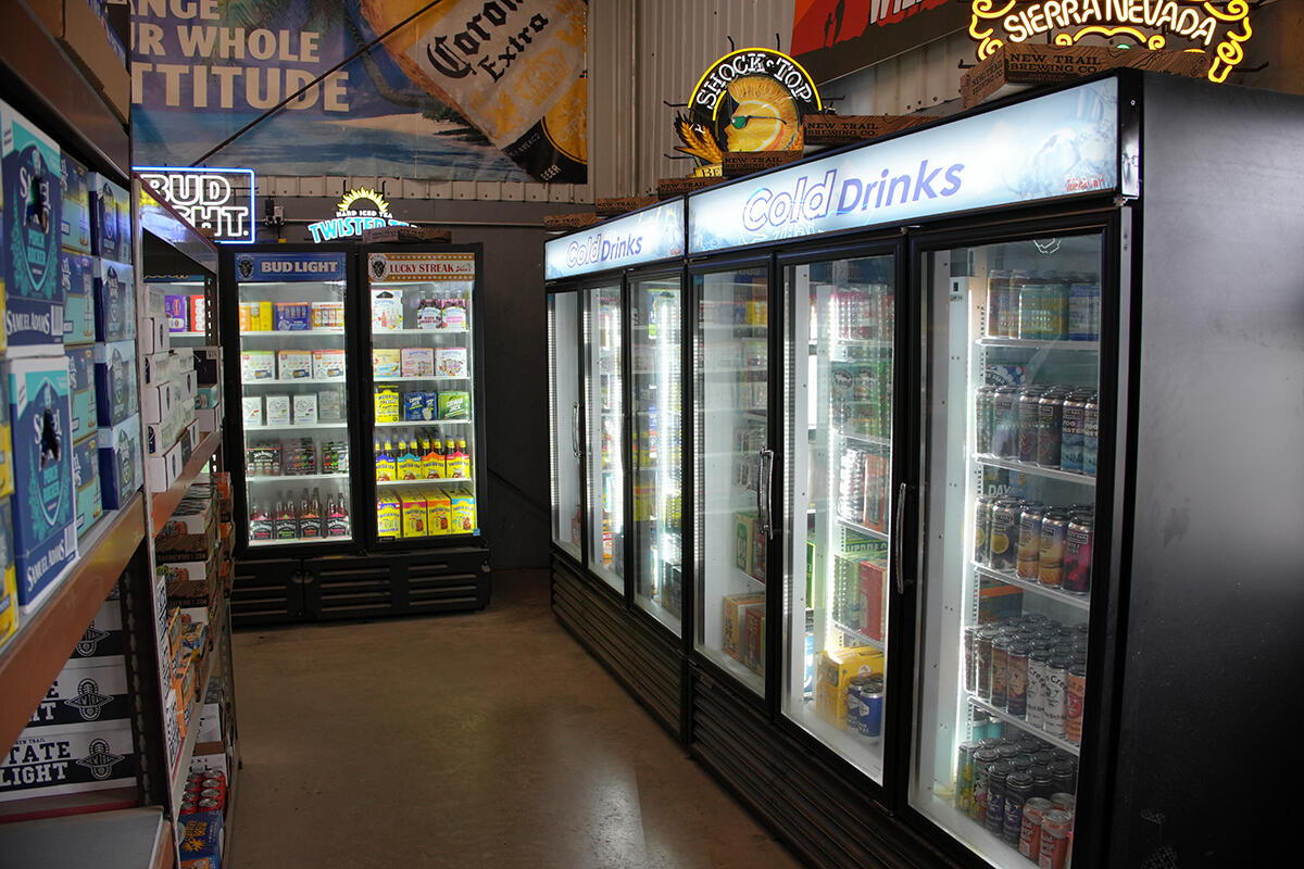 Refrigerated coolers filled with cold beer and beverage selections inside a local beverage store.
